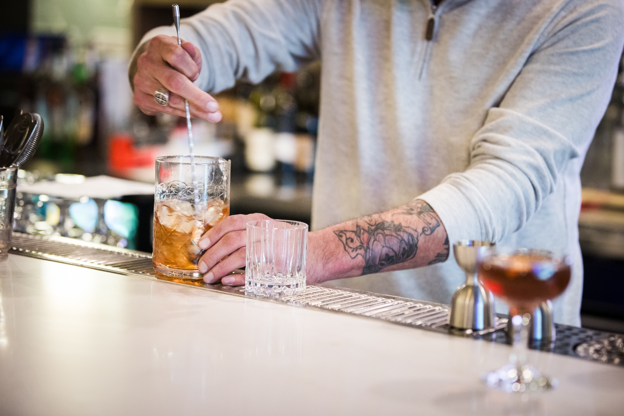 A bartender stirring a craft cocktail behind the bar at Locals Lounge
