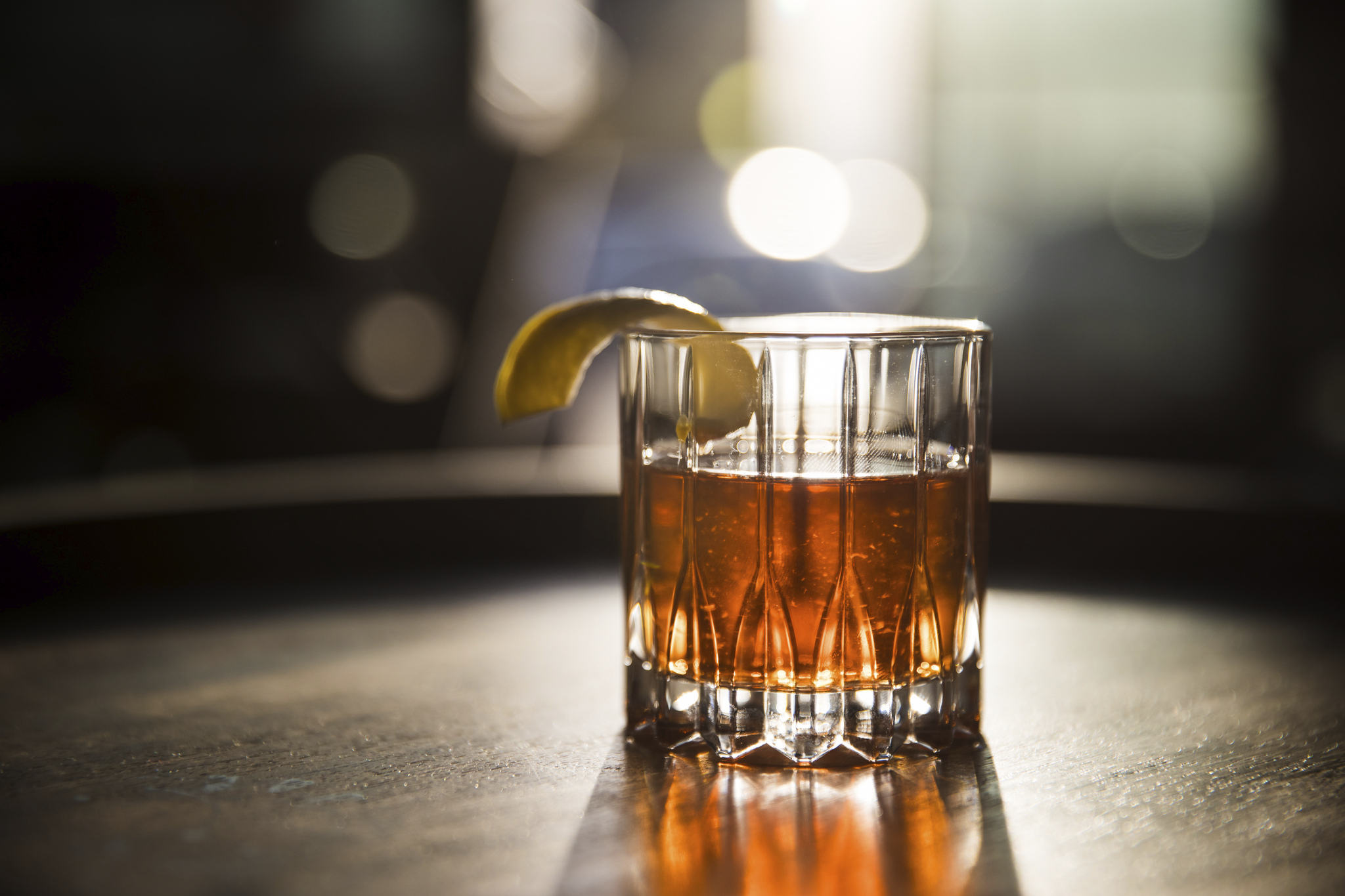 Amber cocktail with a citrus peel glowing in warm bar light