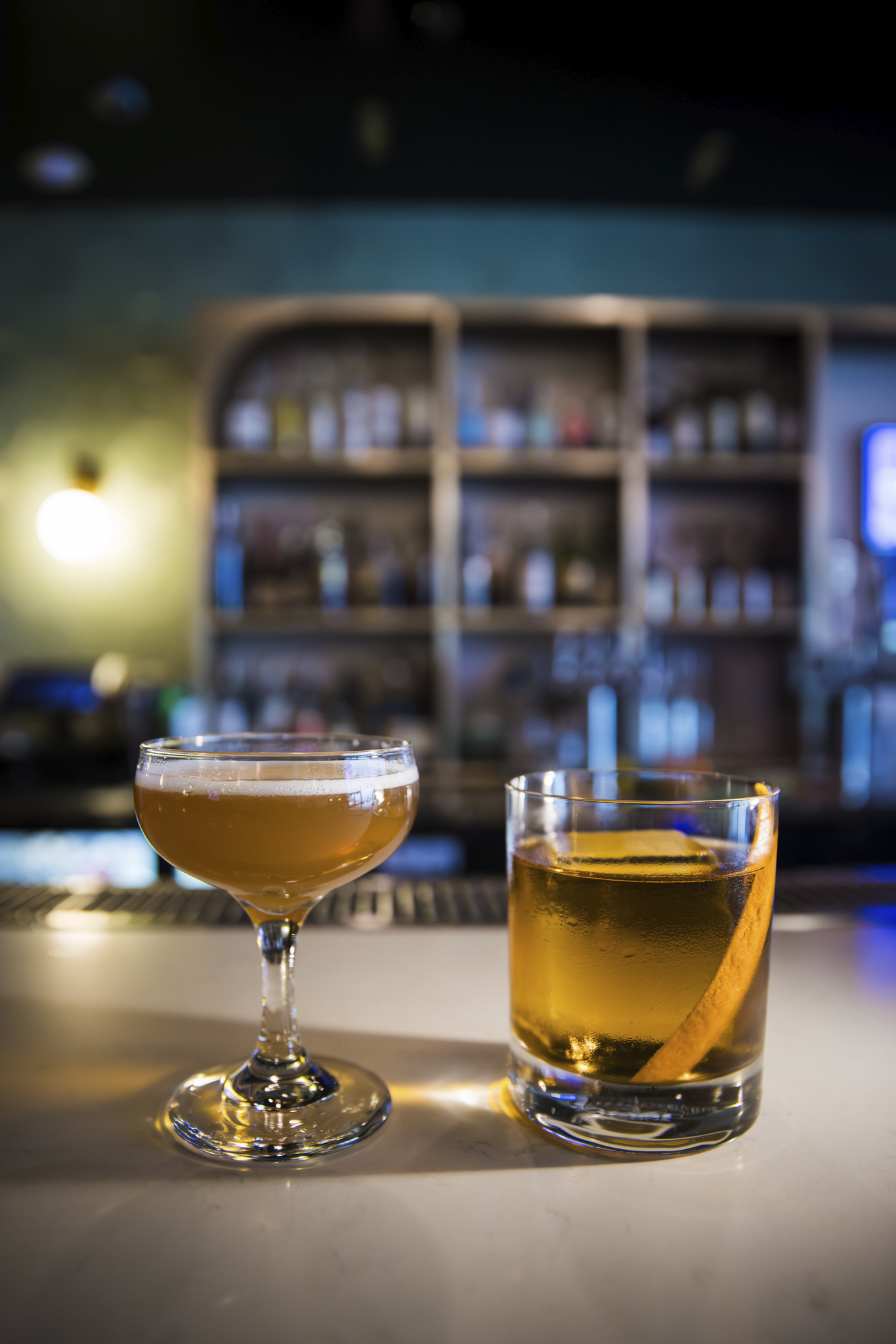 Two amber cocktails at a softly lit bar